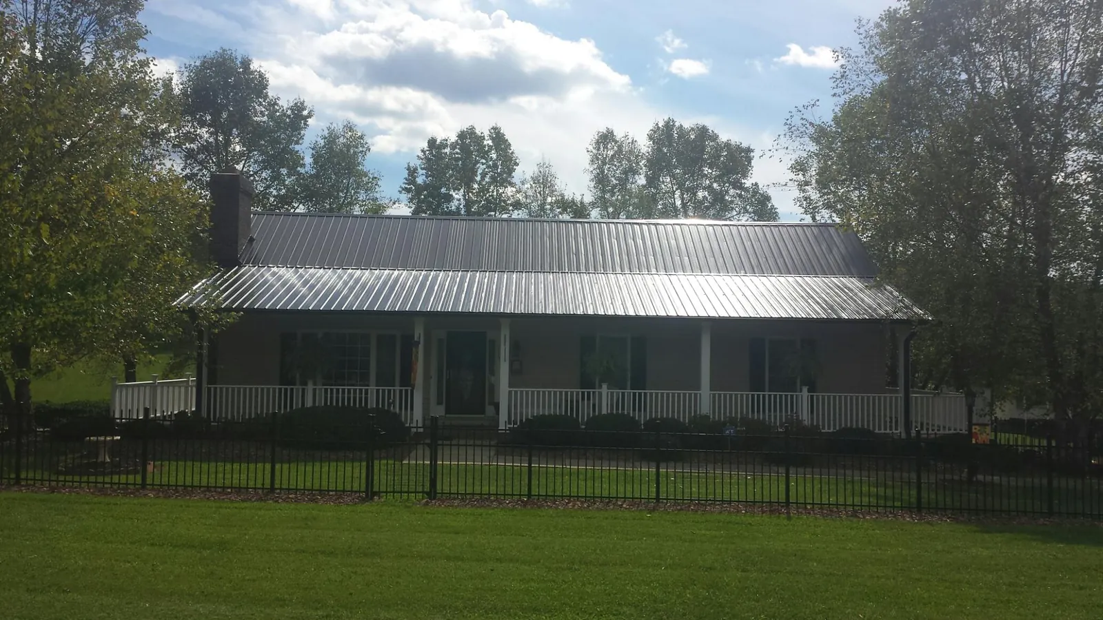 Gray metal roof on a brick ranch with a full width front porch — Gutter Guard Installation work by our crew in Gracey