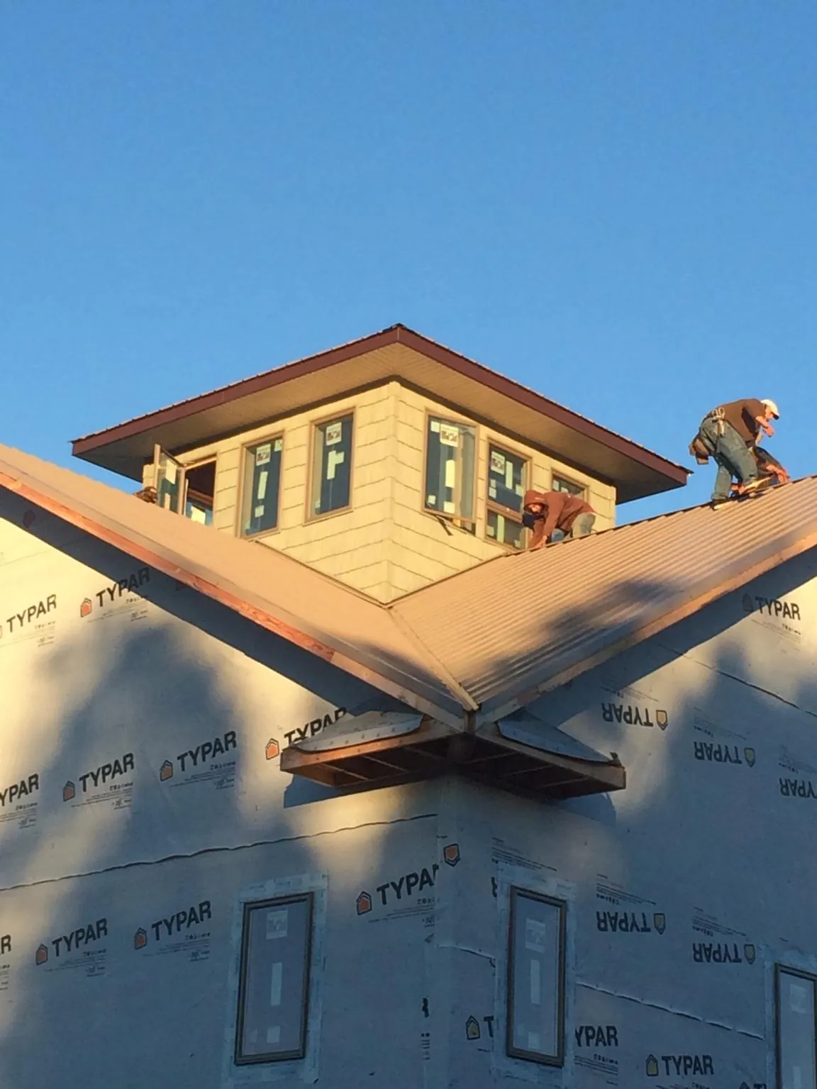 Roofers working around a rooftop cupola on a new metal roof at sunset — Roof Waterproofing in Gracey by Roofing Brothers